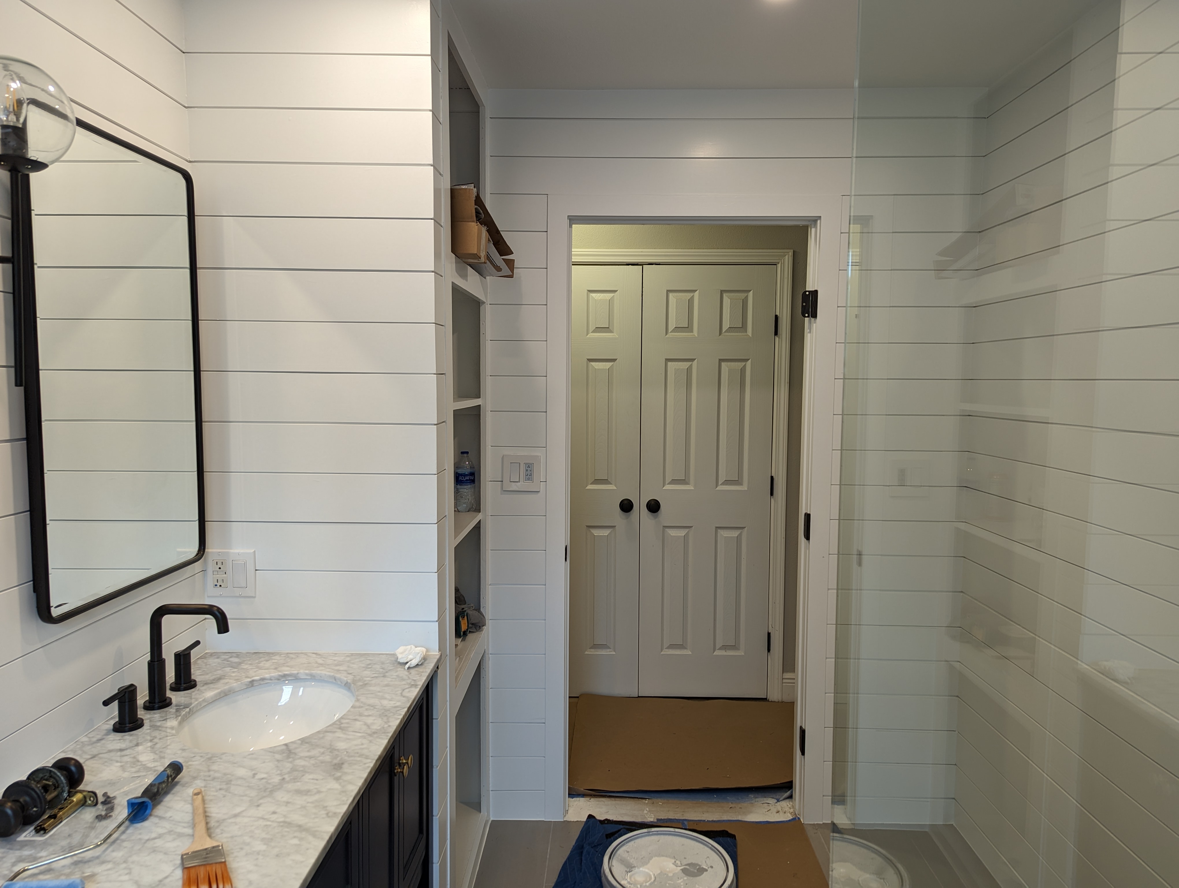 Bathroom renovation in progress with shiplap walls and a marble vanity