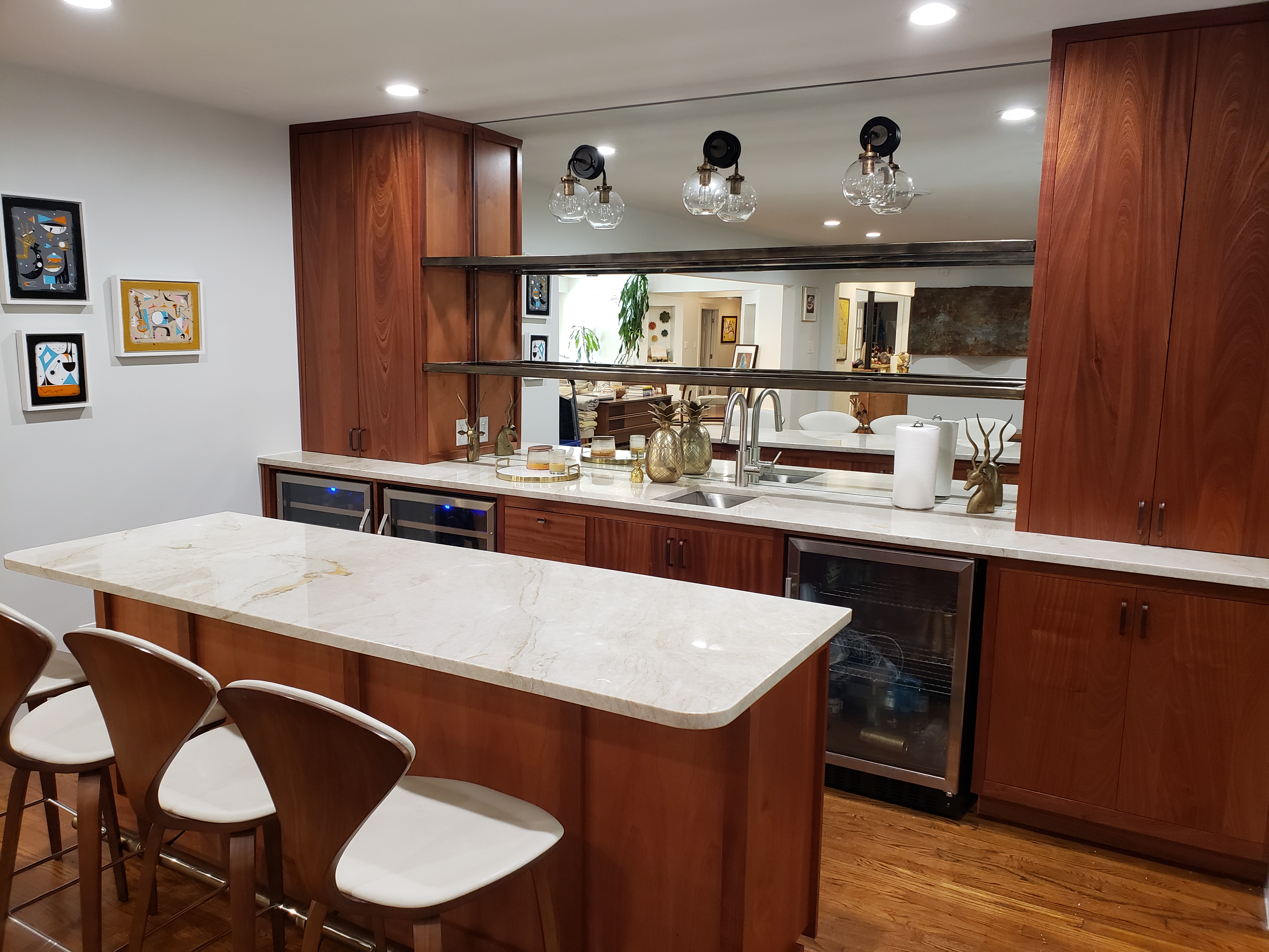 A modern kitchen featuring rich cherry cabinets, a large marble island, and contemporary fixtures.