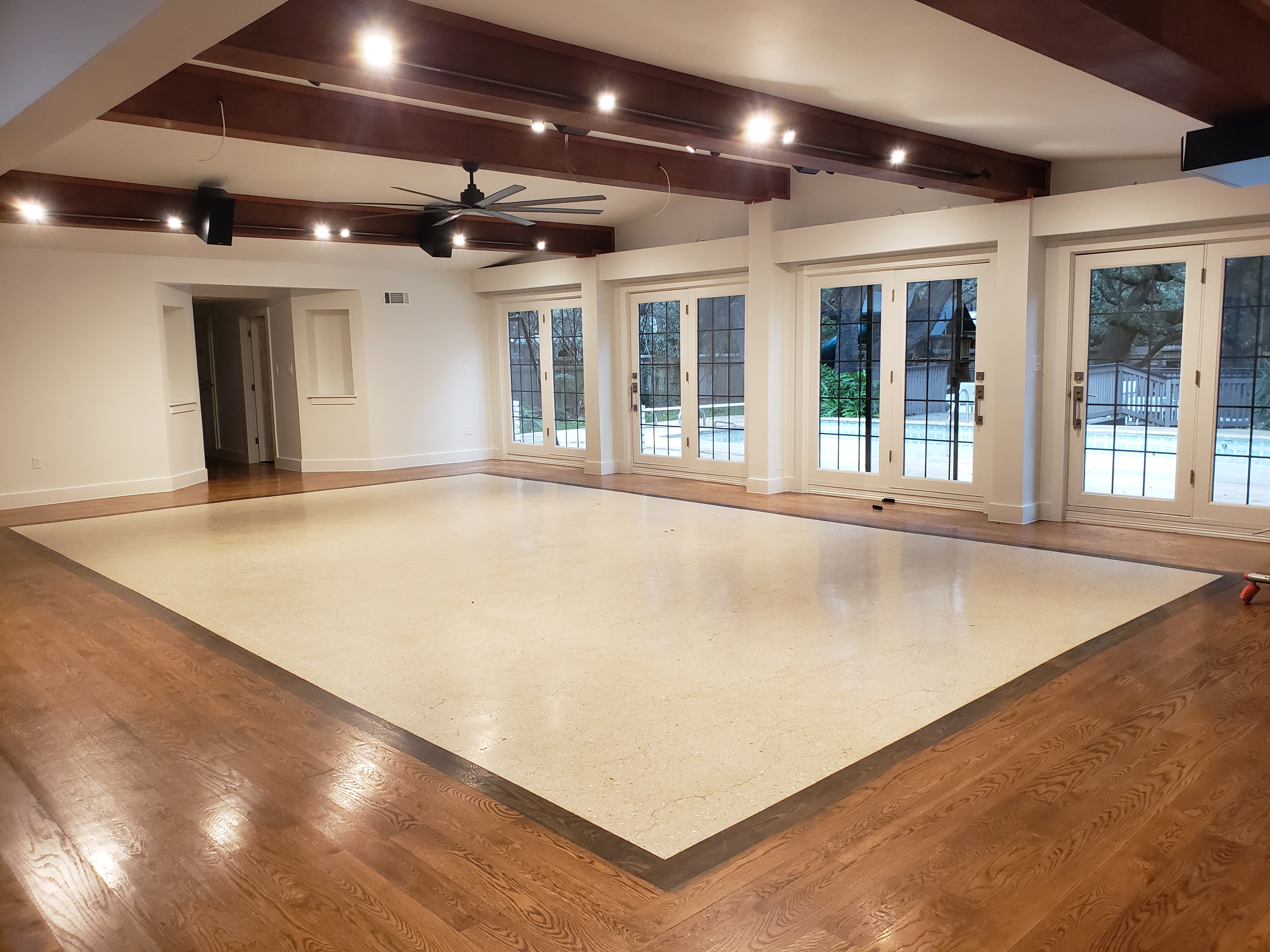 A beautifully remodeled living space featuring exposed beam ceilings, elegant French doors, and warm hardwood flooring.